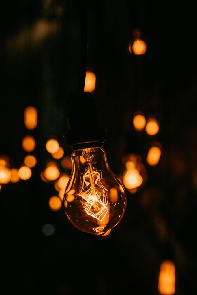 A warmly glowing vintage light bulb in a dark setting, showcasing its filament in detail.